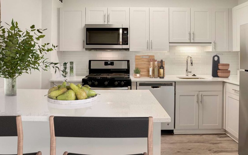 Spacious well lit kitchen with wood floors and stainless steel appliances